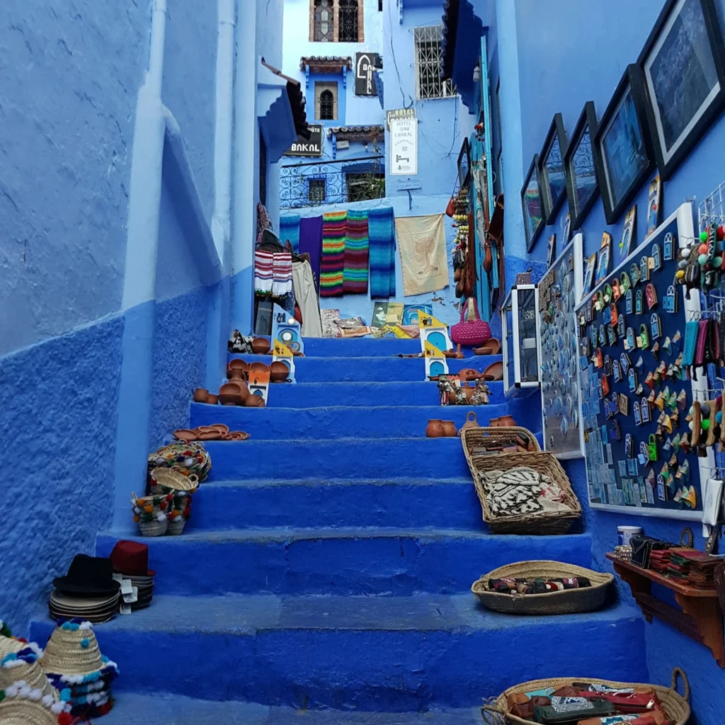 Blue alleyway with flower pots and arched doors in Chefchaouen — holiday to Morocco