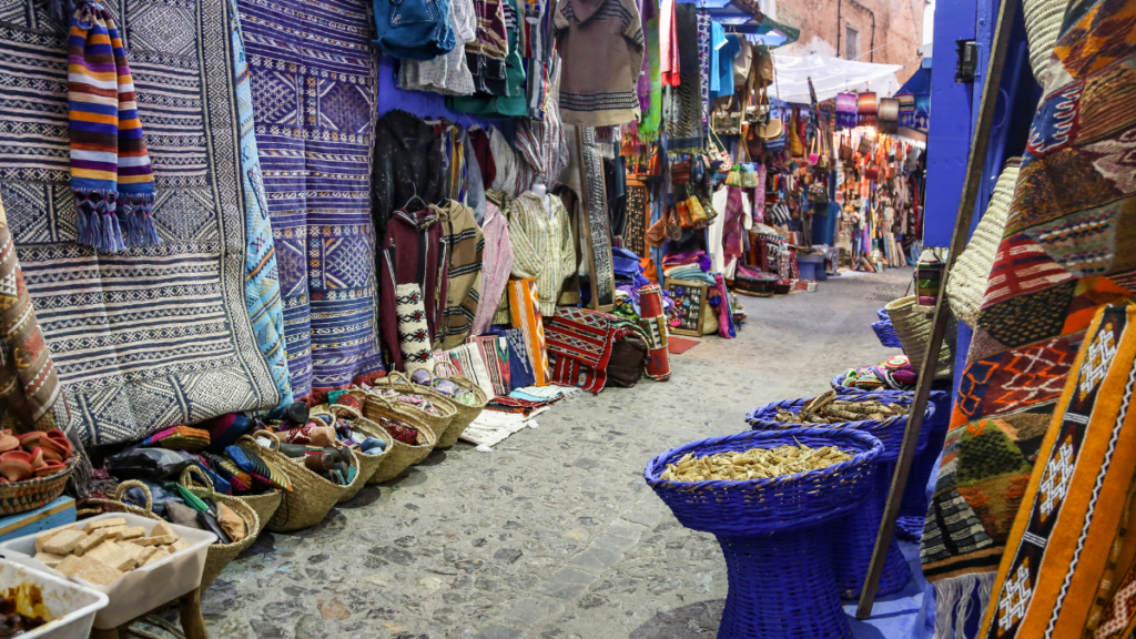 Blue-washed lane with handwoven blankets and baskets in the Chefchaouen medina, Northern Morocco